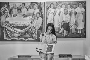 black and white photo of Anna Navasardian sitting and presenting her artwork